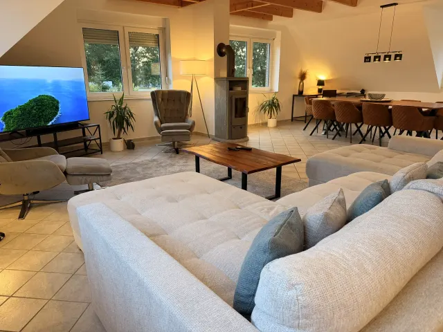 BookNoFees tatil evi: Stuhr – L şeklinde kanepe, odun sobası ve ahşap masalı yemek köşesi bulunan oturma odası