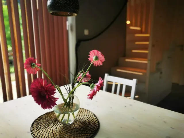 BookNoFees tatil evi: Hieflau, Styria, Avusturya – Beyaz masalı, pembe çiçeklerle dolu vazolu ve ahşap merdivenli yemek alanı